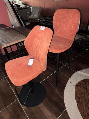 une paire de fauteuils rembourrés orange dans une pièce au sol carrelé marron