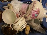 a pile of tea pots and cups in a bin