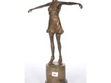 une statue en bronze représentant une femme tenant une raquette de tennis, posée sur un socle