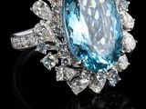 un gros plan d'une bague ornée d'une grosse pierre bleue entourée de diamants