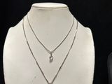 three different necklaces on a mannequin display with a black background