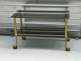 a glass and brass coffee table with wheels on the floor