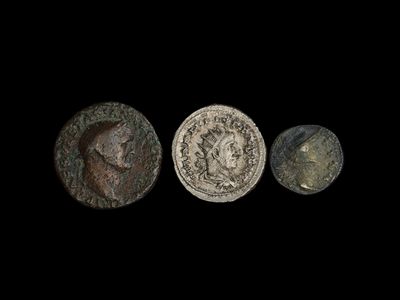 trois pièces romaines, dont l'une représente une tête et l'autre un visage