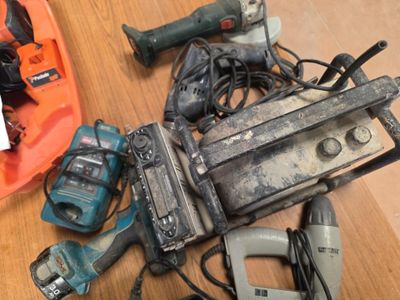 un tas d'outils électriques posés sur une table, à côté d'un casque de chantier