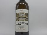 une bouteille de vin posée sur une table à côté d'un mur blanc