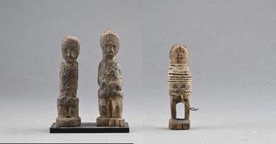 three carved figurines of a man and a woman on a stand