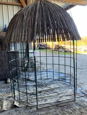 une cage métallique au toit de chaume, au milieu d'une grange
