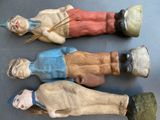 three antique wooden dolls of men and women on a table