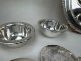 many silver bowls and spoons sitting on a table