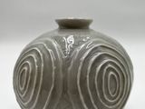 a gray vase with swirl designs on it on a white surface