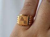 a person holding a gold ring with a letter on it
