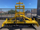 Une grosse machine jaune est garée devant une clôture