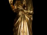 a gold statue of a woman with a hand up