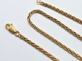 a close up of a gold chain on a white surface
