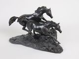 statue of two horses running on a rock on a white background