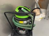 un aspirateur vert et noir posé par terre à côté d'un chien