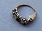 un gros plan d'une bague en or sertie de diamants noirs sur un fond bleu
