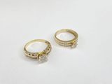 two gold rings with diamonds on them on a white surface