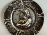 une assiette en argent sur laquelle est représentée une femme