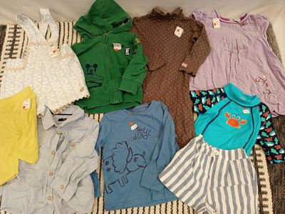 beaucoup de vêtements de bébé qui traînent sur un lit