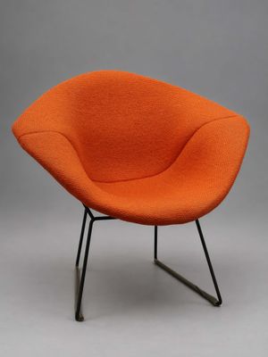 une chaise orange avec des pieds noirs et un piètement noir