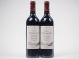 two bottles of red wine sitting next to each other on a white surface