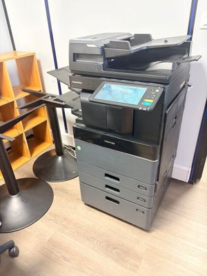 une imprimante multifonction posée sur un bureau, à côté d'une chaise
