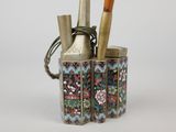 a small vase with brushes in it on a table
