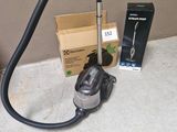un aspirateur posé par terre à côté d'une boîte