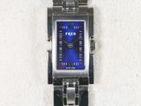 a silver watch with a blue face sitting on a white towel