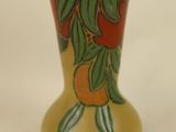 a yellow vase with oranges and leaves painted on it
