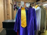 purple and yellow graduation gowns hanging on a rack in a room