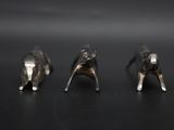 three silver figurines of elephants on a black surface
