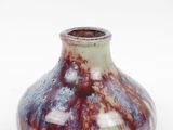 un petit vase posé sur une surface blanche