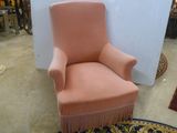 une chaise rose ornée de franges dans une pièce