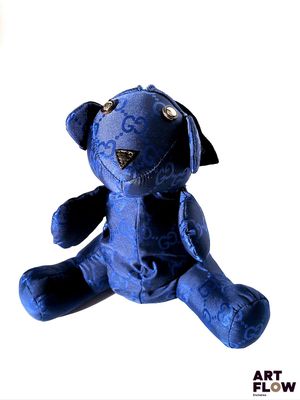 un ours en peluche bleu assis sur une surface blanche