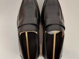 mocassins en cuir noir avec des boucles dorées sur fond blanc