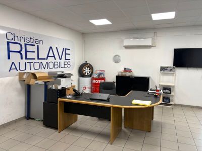 un bureau sur lequel se trouve un ordinateur, dans une pièce où est accrochée une affiche au mur