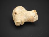 une ancienne figurine en pierre représentant un chien, sur un fond noir