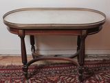 an oval table with a marble top on a rug in front of a white wall