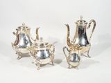 two silver teapots and a coffee pot on a stand