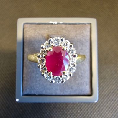 une image d'une bague avec une pierre rouge entourée de diamants blancs