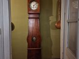 une horloge de parquet posée dans l'embrasure de la porte d'une maison