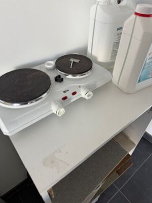 une cuisinière à deux feux sur laquelle est posée une bouteille de liquide