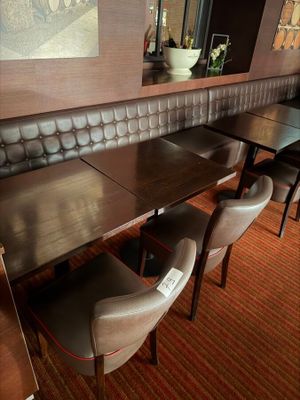 tables and chairs in a restaurant with a picture on the wall behind them