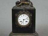 a small clock with a statue on top of it