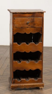 un vieux casier à vin en bois surmonté d'un porte-bouteille
