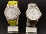 une paire de montres avec des bracelets verts, exposées sur un fond noir
