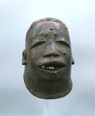 statue représentant le visage d'un homme posée sur un socle, avec un ciel nuageux en arrière-plan