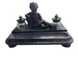 statue représentant un garçon assis sur un plateau sur lequel sont posés des jarres